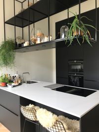 Mooie zwarte keuken met kookeiland waarboven een restaurantrek met accessoires