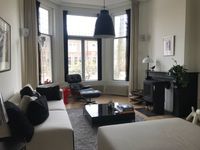 Zitkamer in Jugendstil huis met lichte bank, poef en Eames stoel